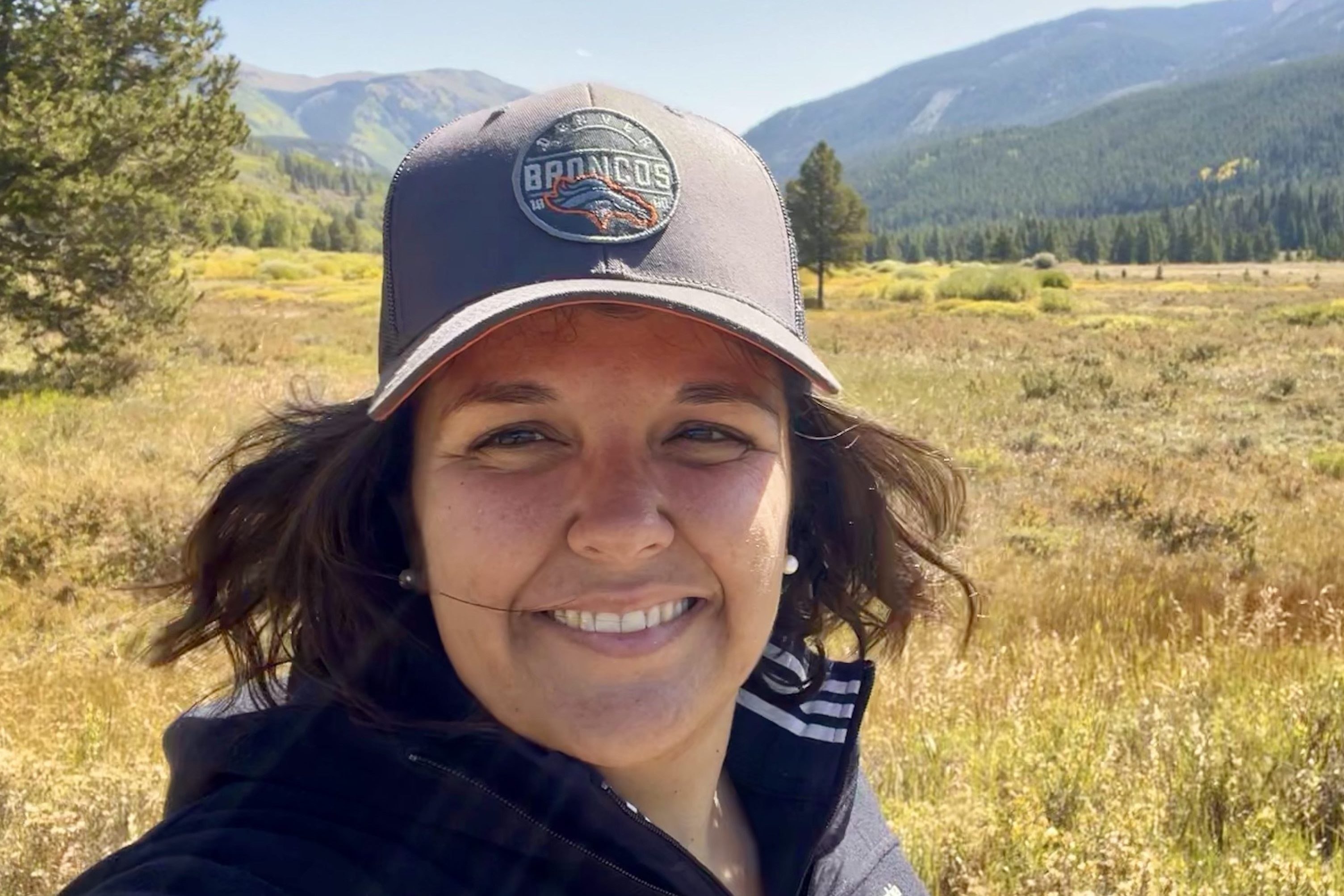 Femme tenant un micro et parlant dans un jardin, en noir et blanc.